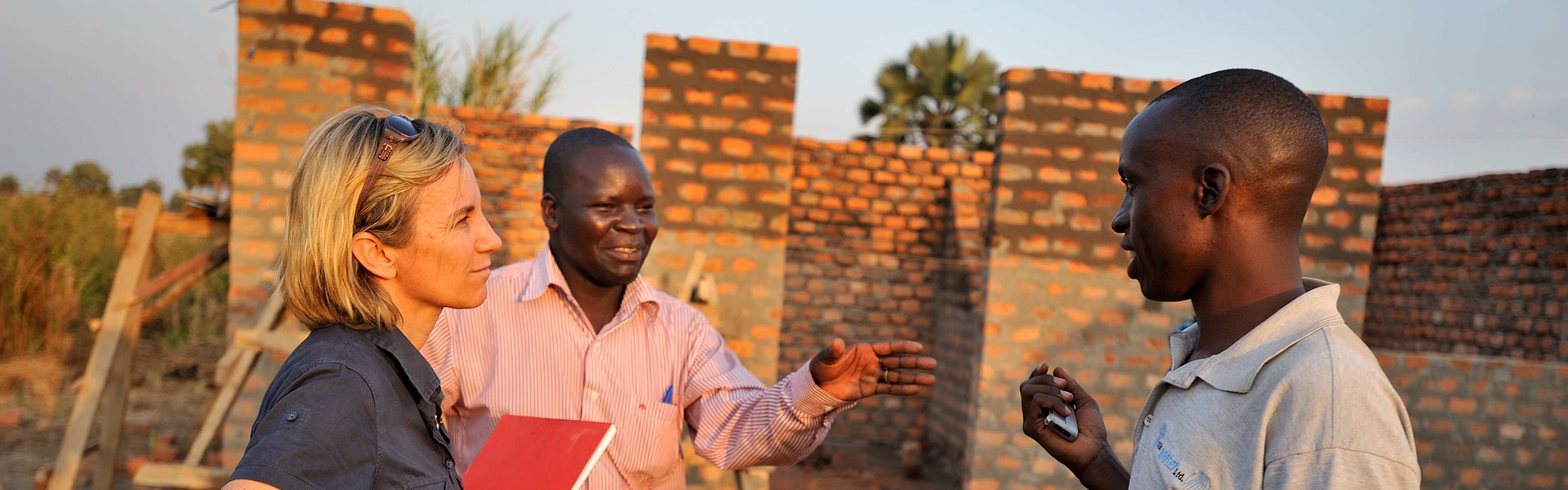 alt-Trois personnes discutant sur un chantier en Ouganda