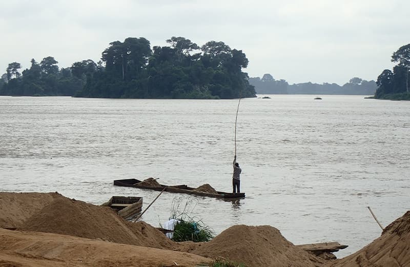Fleuve Sanaga et sa zone estuarienne, homme sur petit bateau en train de travailler